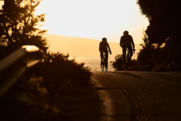 two road cyclist, cycling along a road during sunset cycling into the shadows of the trees and bushes. Ross Woodhall - Action & Lifestyle Photography