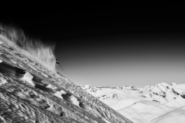 Skier skiing away, down the mountain, off piste with snow covered mountains in the background. Ross Woodhall - Action & Lifestyle Photography