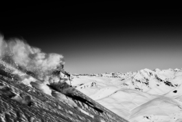 Skier off piste, skiing away from the camera with snow covered mountains in the background. Image in black and white. Ross Woodhall - Action & Lifestyle Photography