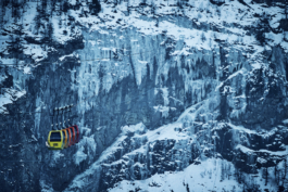 Set of multi coloured ski telecabines heading towards the slopes with a icy cold looking mountain in the background. Le Meije. In the Massif des écrins range Ross Woodhall - Action & Lifestyle Photography