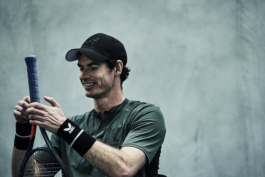 UK tennis player Andy Murray sat looking at his tennis racket smiling. Wearing AMC clothing. Andy Murray Castore. Ross Woodhall - Action & Lifestyle Photography