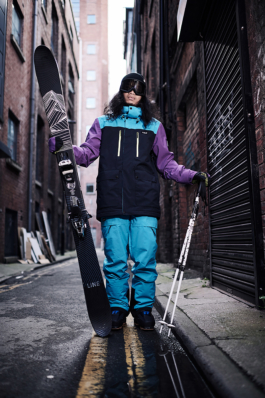 Man wearing ski wear as streetwear but has a pair of skis with poles. In a side street in Manchester. Ross Woodhall - Action & Lifestyle Photography