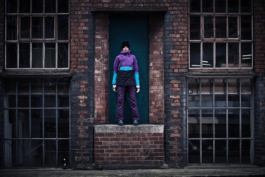 Woman wearing winter ski wear as streetwear in Manchester side street, wearing ski boots, gloves and googles. Ross Woodhall - Action & Lifestyle Photography
