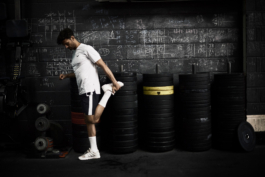 man stretching for workout in gym in front of chalk board, wearing Castore. Ross Woodhall - Action & Lifestyle Photography