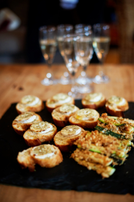 Appetisers on a slate plate with champagne glasses in the background. Ross Woodhall - Action & Lifestyle Photography