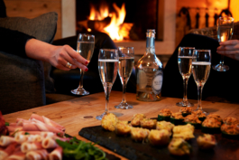 Appetizers with six champagne glasses in front of the fire with two drinking. Ross Woodhall - Action & Lifestyle Photography