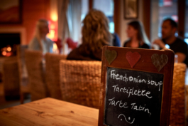 dinner meal with dinning table and guest in the background in the chalet with a fire. Ross Woodhall - Action & Lifestyle Photography