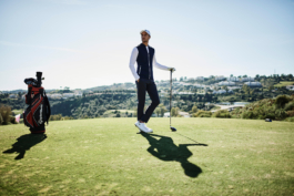 Man posing whilst playing golf wearing Castore clothing with golf club, a clear sunny day with building/houses in the background. Ross Woodhall - Action & Lifestyle Photography