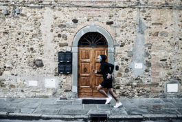 male runner, jogging along, outside, on an old pavement with a big wooden door. Ross Woodhall - Action & Lifestyle Photography