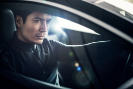 Man wearing a Mclaren Castore top in a Mclaren sports car looking through his side window. Ross Woodhall - Action & Lifestyle Photography