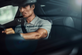 Man driving a Mclaren sports car wearing a Mclaren Castore top, looking through the windowscreen. Ross Woodhall - Action & Lifestyle Photography