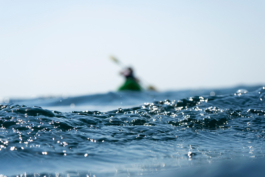 taken from the water, in the distance a blurry kayak with two kaykers. Ross Woodhall - Action & Lifestyle Photography