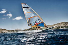 Windsurfer going across the image, front of board out of the water. Land in the background. Ross Woodhall - Action & Lifestyle Photography