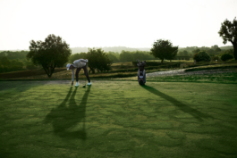 Man playing golf, placing a golf tee on the course with golf bag beside him. Ross Woodhall - Action & Lifestyle Photography