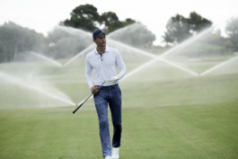 Man playing golf, wearing a golf glove and holding a golf club. Sprinklers, on behind Ross Woodhall - Action & Lifestyle Photography