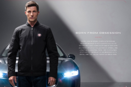 Man stood in front of Jaguar with headlight on wearing a black zipthrough Jaguar branded jacket. Ross Woodhall - Action & Lifestyle Photography