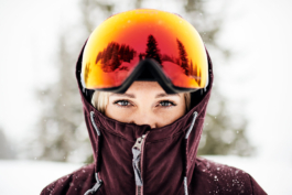 woman skier looking straight at the camera, wearing a jacket with hood over the helmet with goggles. Ross Woodhall - Action & Lifestyle Photography