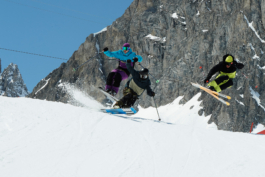 three skiers coming down the slope, two mid air, coming over the brim of the hill. Ross Woodhall - Action & Lifestyle Photography