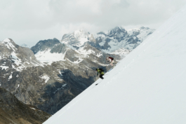 two skiers skiing off piste with mountains in the background. Ross Woodhall - Action & Lifestyle Photography