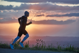 male runner, jogging along a road with wild flowers as the sun is setting. Ross Woodhall - Action & Lifestyle Photography