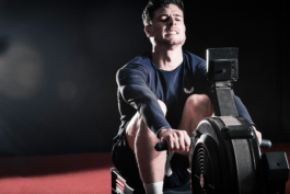 Man on rowing machine, looking at screen on rower, wearing Castore. Ross Woodhall - Action & Lifestyle Photography