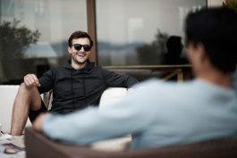 Two men relaxing outside on a sofa facing each other, wearing Castore clothing and sunglasses. Ross Woodhall - Action & Lifestyle Photography