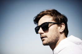 Man wearing sunglasses with the brand name Castore, slight beard growth. Clear blue sky behind him. Ross Woodhall - Action & Lifestyle Photography