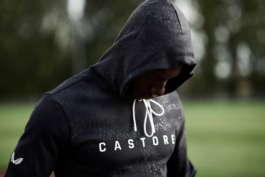 Black man wearing Castore waterproof hoodie with hood up, with water droplets clinging to the hoodies surface. Ross Woodhall - Action & Lifestyle Photography