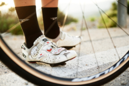 Close up on cycling shoes, socks pulled up, through front cycling tyre. Ross Woodhall - Action & Lifestyle Photography