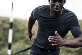 Black/ethnic/coloured man running close up past camera wearing black t shirt. Ross Woodhall - Action & Lifestyle Photography