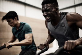 two men working out in gym, competing with each other on machines, getting sweaty, wearing Castore, Ross Woodhall - Action & Lifestyle Photography
