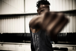 male in gym, punching towards the camera, with weights lined up behind. Ross Woodhall - Action & Lifestyle Photography
