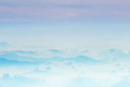 Image of mountain peaks surrounded by clouds, all in pale colours. Ross Woodhall - Action & Lifestyle Photography