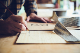Man working on his bamboo skis in his workshop, pencilling out the shape of the skis. Ross Woodhall - Action & Lifestyle Photography