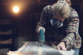 Man working on a pair of bamboo skis with a machine and face, mouth protection mask. Ross Woodhall - Action & Lifestyle Photography