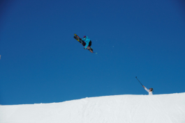 skier in mid air doing a grab whilst another skier holds a go pro up to video. Ross Woodhall - Action & Lifestyle Photography