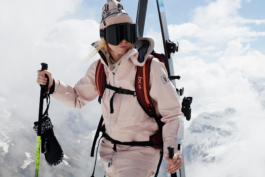 close up of female skier, carrying skis, strapped to backpack with gloves hanging from her hands. Ross Woodhall - Action & Lifestyle Photography