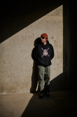 man standing against a concrete wall wearing a hat with glasses. Ross Woodhall - Action & Lifestyle Photography