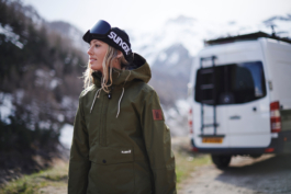 woman wearing winter jacket with hat and googles with a converted van in the background. Ross Woodhall - Action & Lifestyle Photography