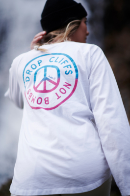 female with white long sleeved top on with Drop cliffs not bombs. wearing a black woolly hat. Ross Woodhall - Action & Lifestyle Photography