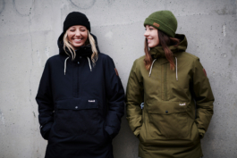 two females wearing woolly hats and winter jackets in front on a concrete wall. Ross Woodhall - Action & Lifestyle Photography