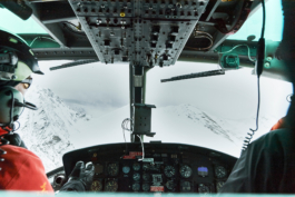 View from inside a helicopter with the pilot & front passenger flying above the snowy mountains. Ross Woodhall - Action & Lifestyle Photography