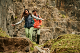 A couple, man and a woman out hiking/walking for the day. Woman has arms slightly out, looks like she is balancing. Stoney hill, Cheddar Gorge in background. Ross Woodhall - Action & Lifestyle Photography