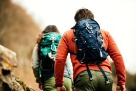 A couple, man and woman hiking/walking up a hill wearing fleeces and small backpacks Ross Woodhall - Action & Lifestyle Photography
