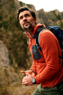 Man wearing a orange fleece and backpack looking up into the hilss. Ross Woodhall - Action & Lifestyle Photography