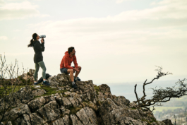 A couple, man and woman having a break on a stony ridge with views towards the valley. Ross Woodhall - Action & Lifestyle Photography