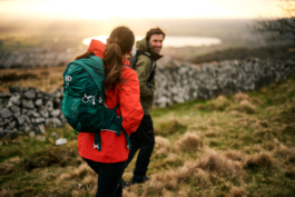A man and a woman out walking/hiking. Walking by a stone wall with a lake in the distance. Ross Woodhall - Action & Lifestyle Photography