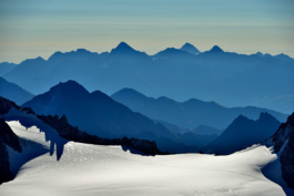 Photo of mountain lines in different distances that are different shades of blue taken from a snowy mountain top on a sunny day. Ross Woodhall - Action & Lifestyle Photography