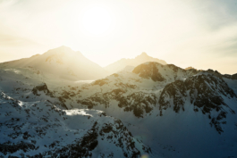 Image of some mountains covered in snow with the sun shinning straight in front of you. Ross Woodhall - Action & Lifestyle Photography
