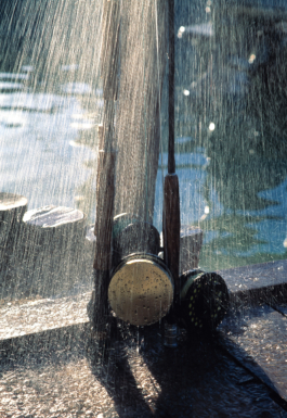 three fly fishing reels propped up, with a shower of water rinsing them off against the harbour side. Ross Woodhall - Action & Lifestyle Photography